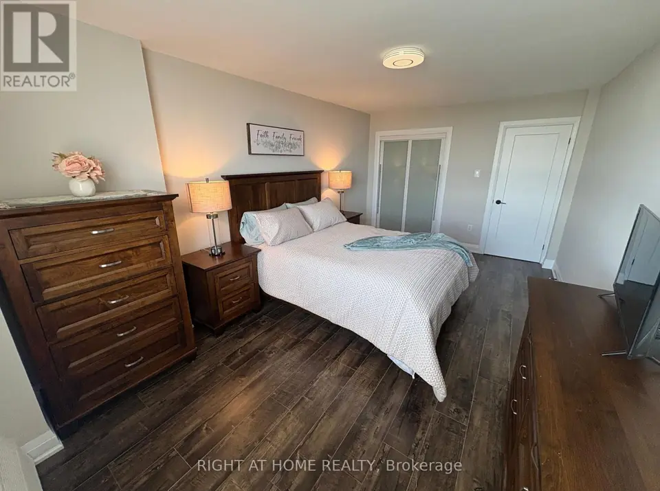 Bedroom with wooden bed and dressers, frosted-glass sliding closet doors and white door in the background.