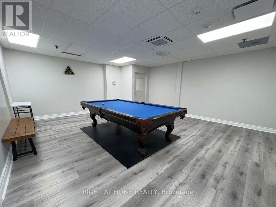 Recreation room with a blue-felt billiards table on a dark mat, wooden bench and grey plank flooring.